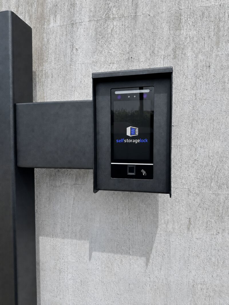 FRU display terminal in a black housing on a concrete wall, showing the SELFSTORAGELOCK logo on its screen